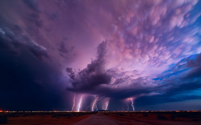 Lightning strikes over a desert landscape at dusk