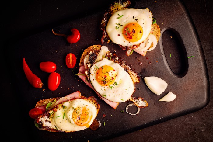Fried eggs on toast with ham and tomatoes
