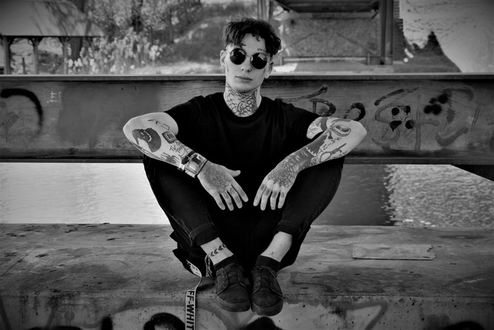 Young man with tattoos and glasses sitting
