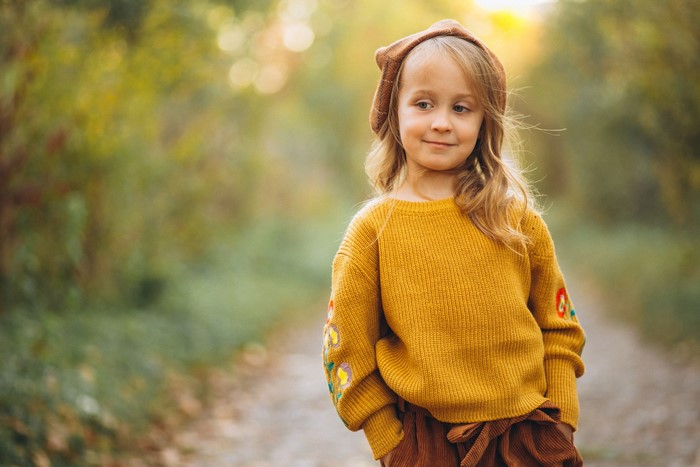 Little girl in a yellow sweater and brown hat