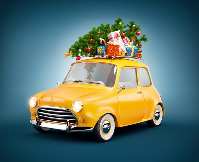 Yellow car with Christmas tree and gifts on roof