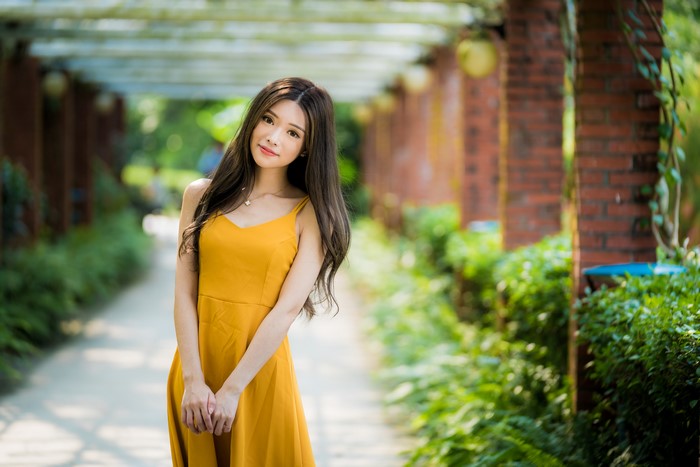 Asian woman in yellow dress posing outdoors