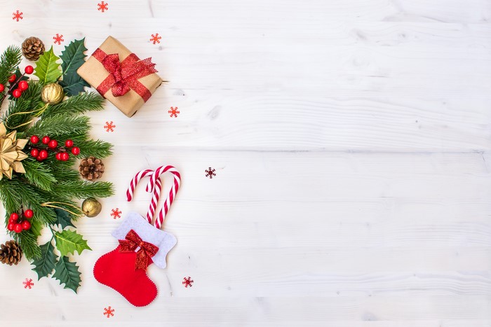 Christmas branches, gift, and candy canes on white wood