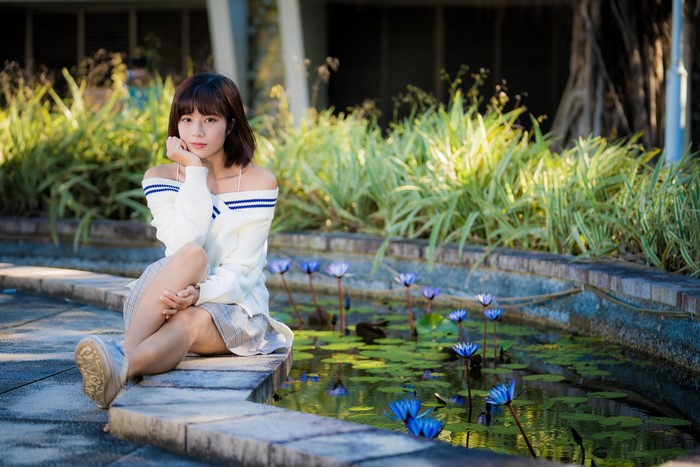 Asian girl sitting by a pond with water lilies