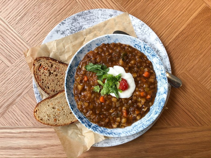 Bowl of lentil soup with bread on a plate
