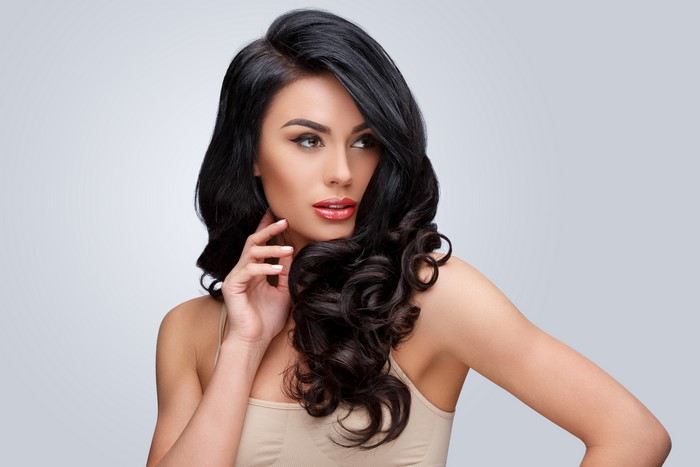 Brunette girl with beautiful hairstyle on gray background
