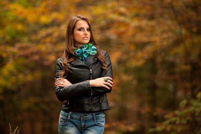 Woman in leather jacket and jeans in autumn forest