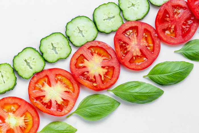 4K Sliced Tomatoes, Cucumbers, and Basil on White Background