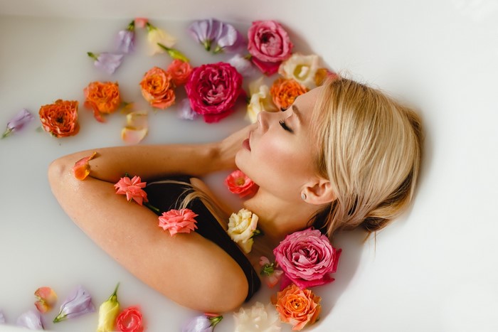 Blonde woman relaxing in a milk bath with flowers