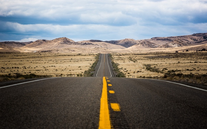 Empty desert highway stretching towards distant mountains