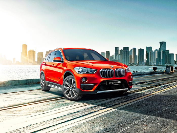 Red BMW X1 Urbanista parked by a city skyline