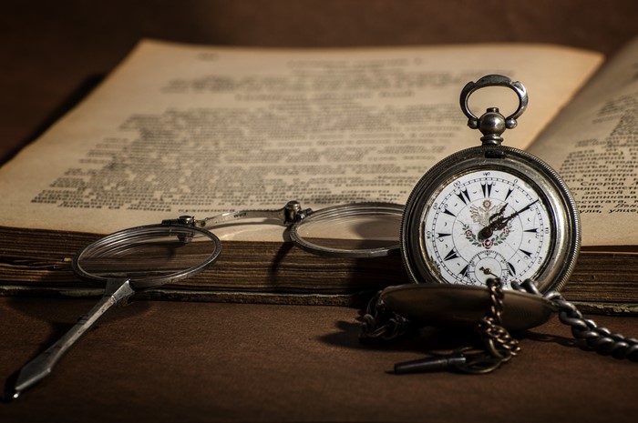 Pocket watch and glasses on an open book