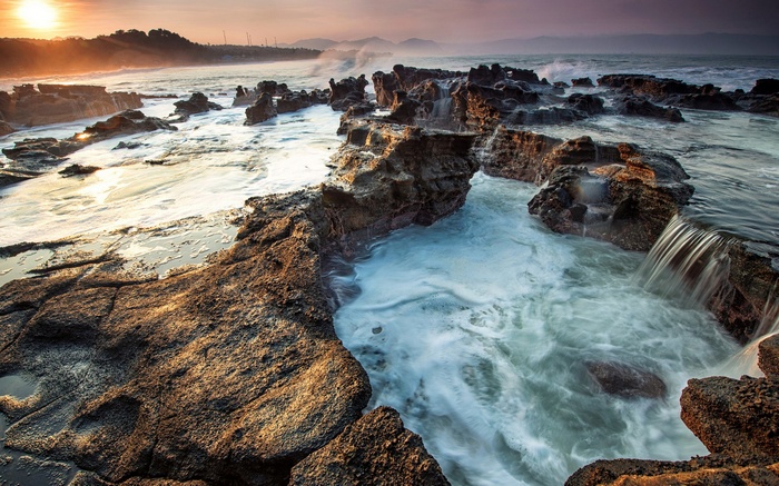 Rocky coastline with waves crashing at sunset