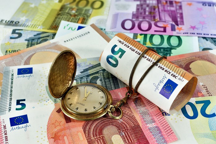 Euro banknotes and a pocket watch