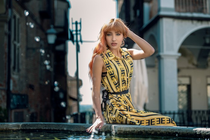 Woman in yellow dress sitting by a fountain