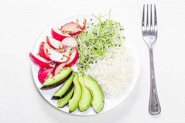 Rice bowl with radishes, avocado, sprouts, and a fork