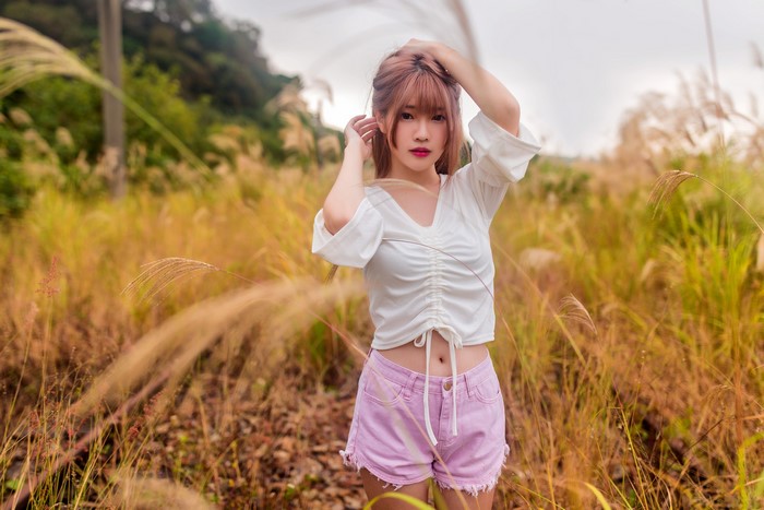 Asian woman with brown hair posing in a field