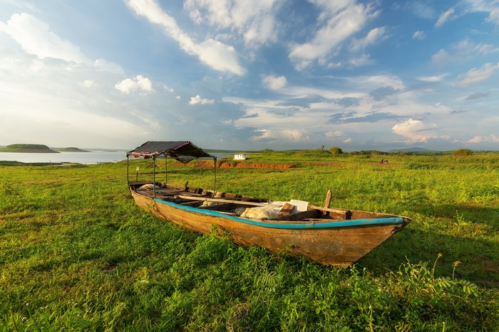 Boat on grassy shore with lake and sky