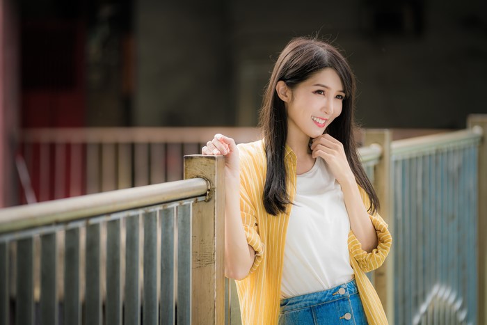 Asian woman with brown hair smiling, wearing yellow shirt