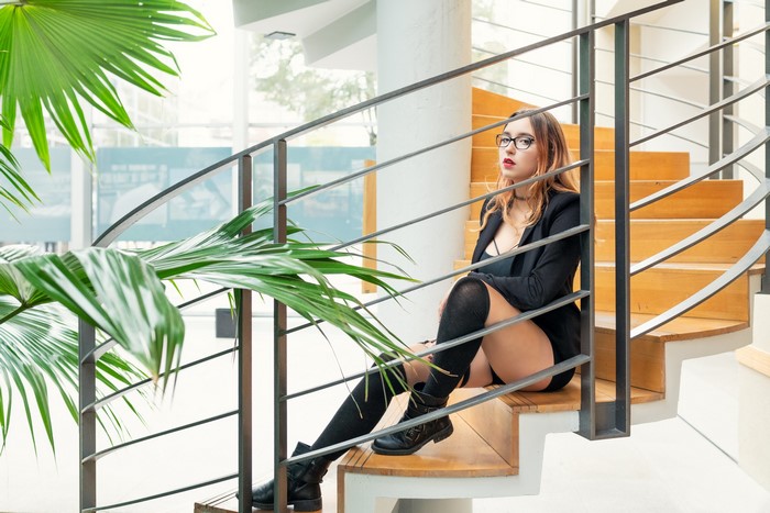 Woman in glasses and blazer sitting on stairs