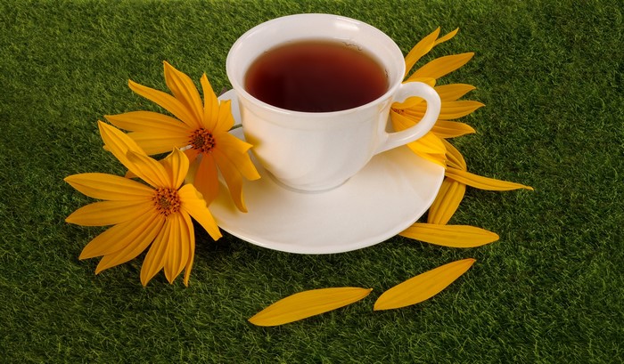 White teacup with yellow flowers on green grass