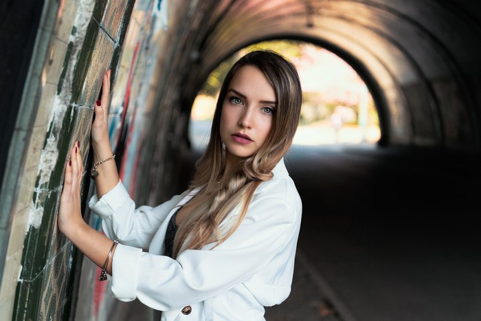 Woman in white jacket in graffiti tunnel