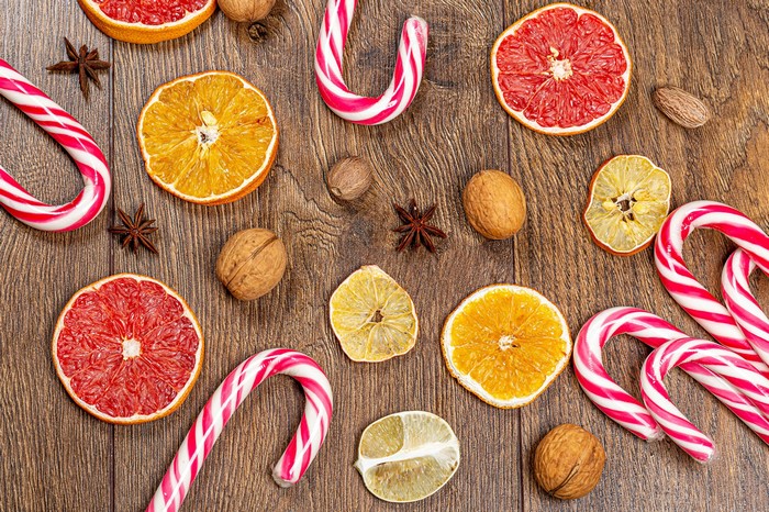 Christmas candy canes and dried citrus slices on wood