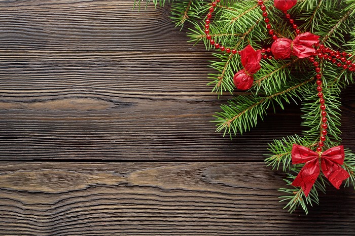 Christmas fir branches with red ornaments on wood