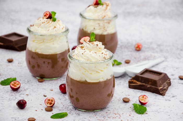 Chocolate dessert in jars with whipped cream and cranberries