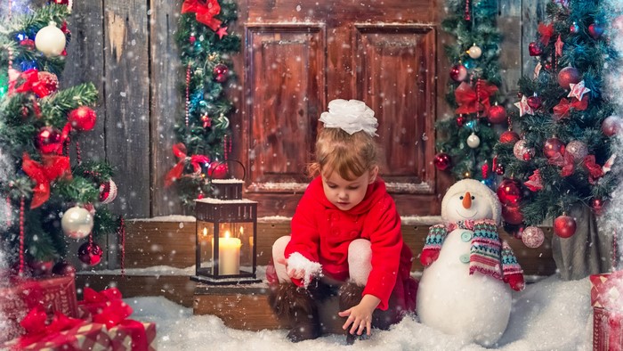 Little girl playing in the snow with Christmas decorations