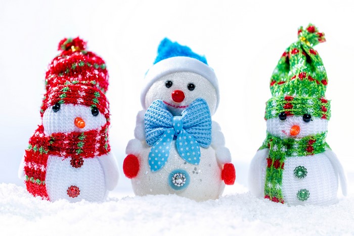 Three snowmen with hats and scarves in the snow