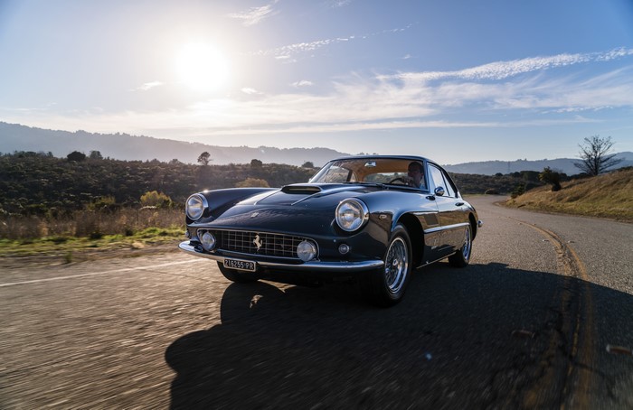 Dark Blue Metallic Ferrari Driving on a Winding Road