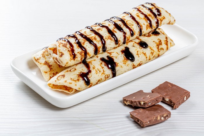 Rolled pancakes with chocolate syrup and chocolate bars