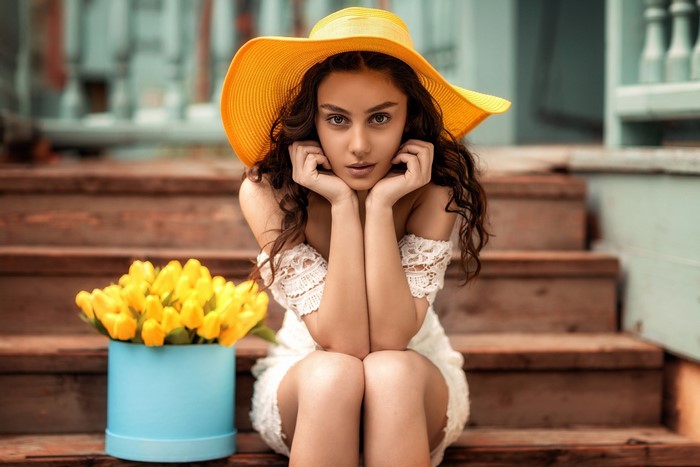 Natia Gachava wearing a yellow hat sitting on stairs with flowers