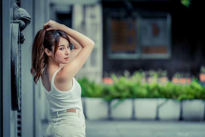 Asian woman with brown hair in white tank top and shorts