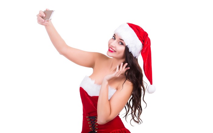 Brunette girl in Santa hat taking a selfie