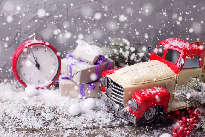 Christmas gifts and toy truck with snow and clock