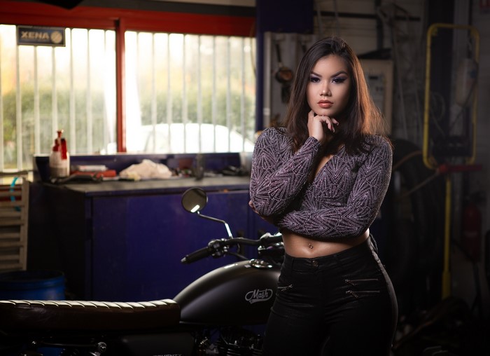 Woman posing in a garage with a motorcycle