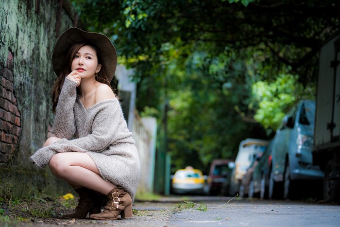 Asian woman wearing a hat and sweater posing