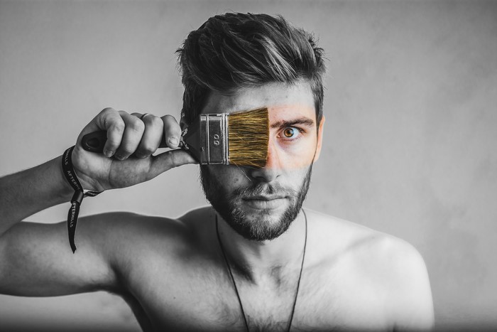 Man holding paintbrush over eye
