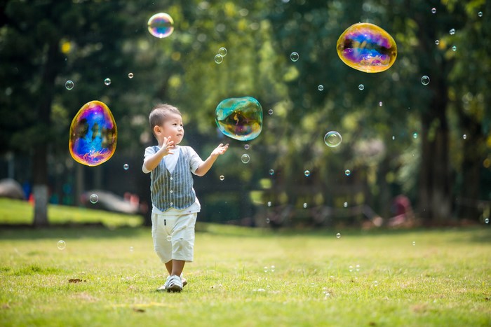Boy playing with soap bubbles in a park