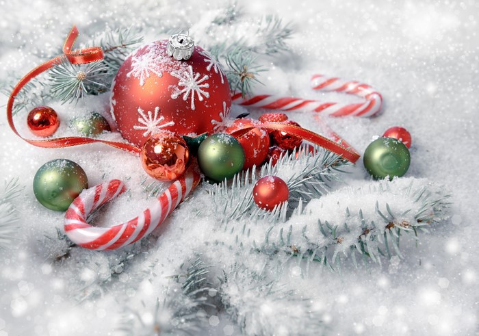 Christmas ornaments and candy canes on snow-covered branches