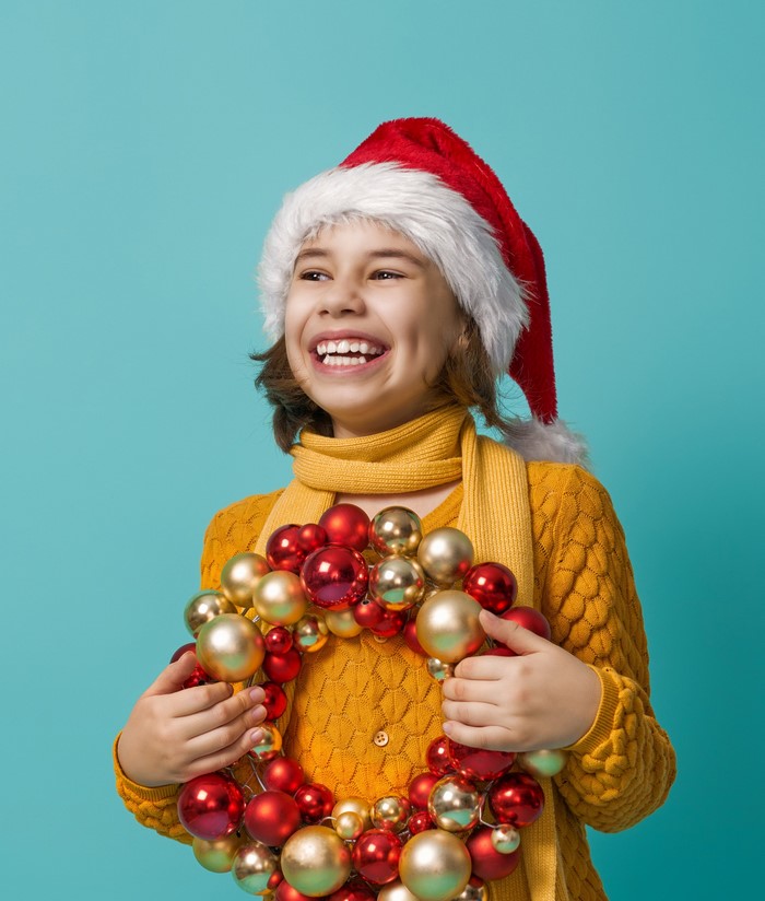 Girl in Santa hat holding Christmas wreath