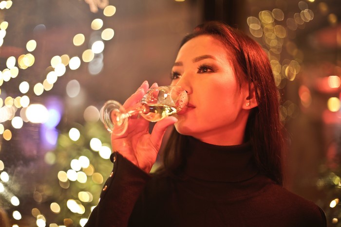 Asian woman drinking wine with bokeh lights