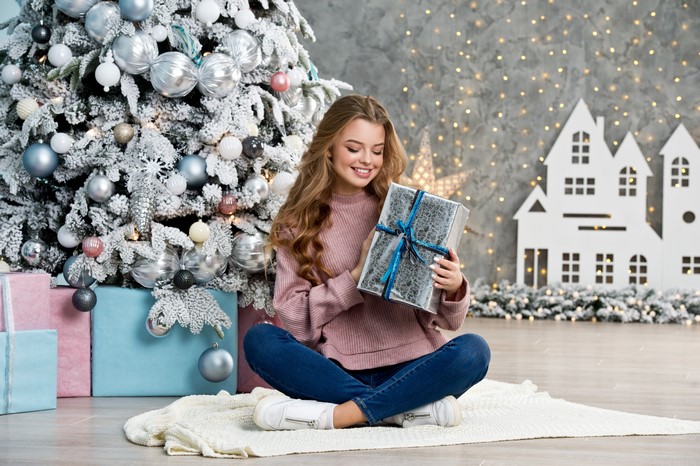Girl with Christmas gift by decorated tree