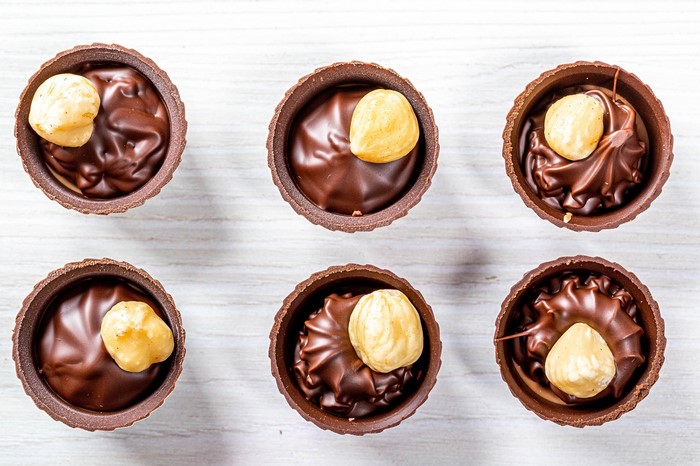 Chocolate candies with hazelnuts on a white wooden table