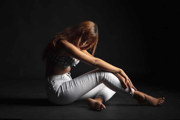 Francesca sitting in white jeans and bra