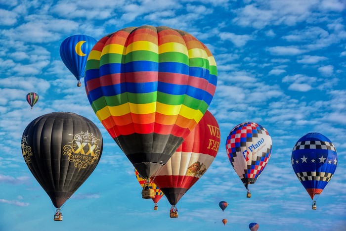 Hot air balloons in flight against a cloudy blue sky