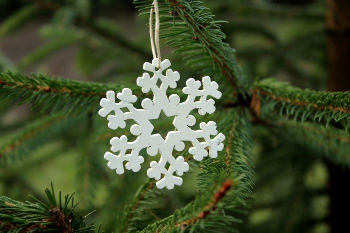 White wooden snowflake ornament on a Christmas tree