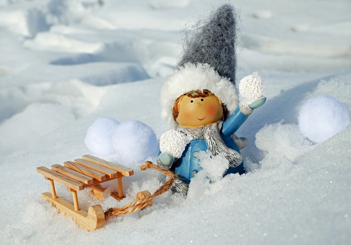 Winter scene with a toy girl, sled, and snowballs